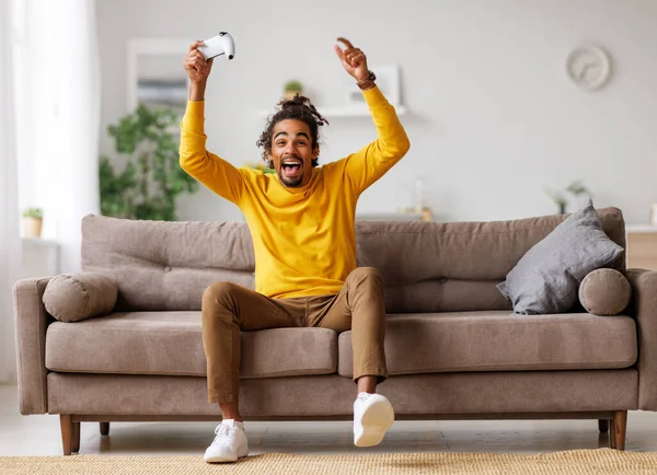 Молодий позитивний щасливий афроамериканський хлопець з бездротовим геймплеєм грає в відеоігри вдома — стокове фото