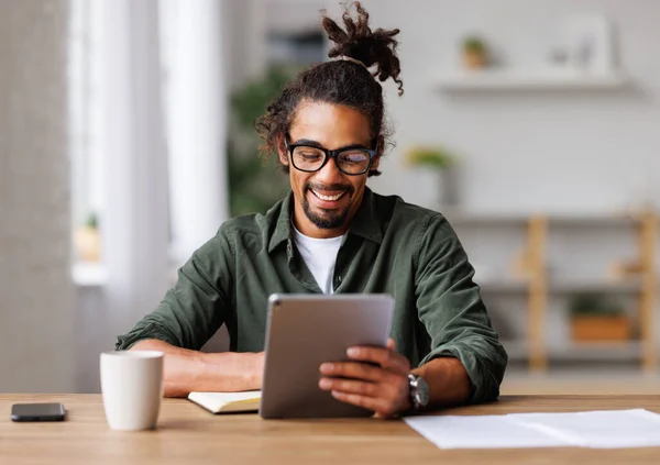 Jonge Afrikaanse Amerikaanse man freelancer werken op afstand op tablet pc of online studeren thuis — Stockfoto