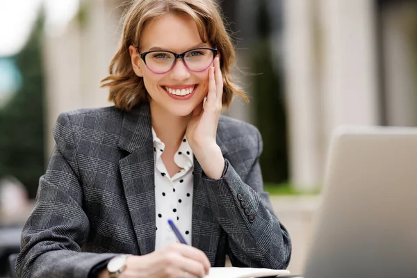 Vacker ung kvinna entreprenör att ta en kopp kaffe medan du håller möte på nätet utanför i café — Stockfoto