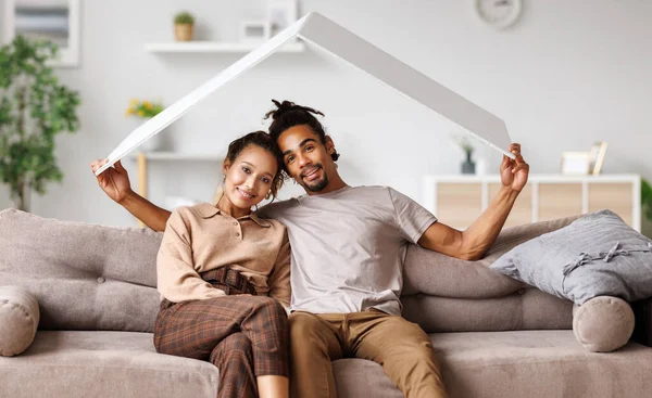 Álmodj otthon. Fiatal boldog afro-amerikai házaspár kezében fehér ház tető fölött — Stock Fotó