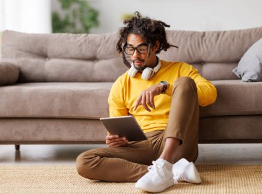 Dijital tabletli genç Afrikalı Amerikalı adam kendini izole ederken video aracılığıyla konuşuyor.