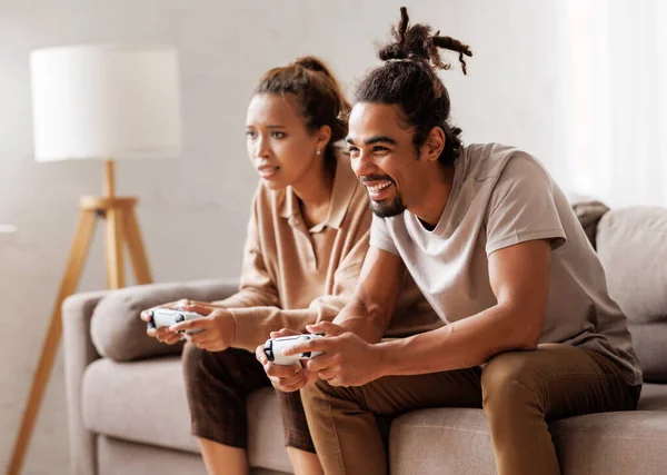 Африканська американська пара сміється і грає в відеоігри разом за допомогою відеогральної консолі. — стокове фото