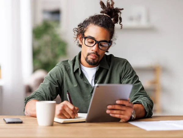 Young african american man freelancer working remotely on tablet or studying online at home — Stock Photo, Image