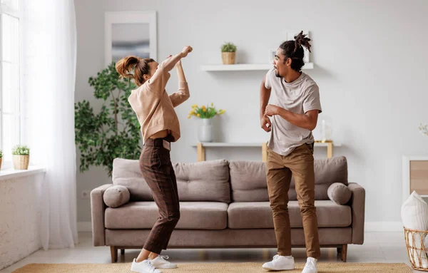 Joven feliz pareja afroamericana de la familia bailando a la música en el sofá en casa —  Fotos de Stock