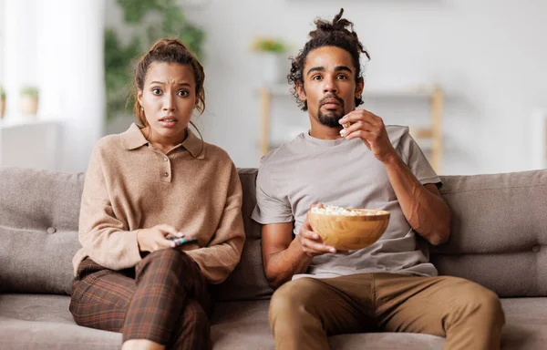 Young scared african american family couple screaming while watching horror movie at home — Stock Photo, Image