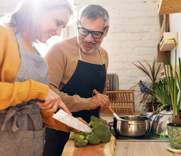 Feliz pareja de ancianos casados cocinando un delicioso y saludable almuerzo juntos en una acogedora cocina — Foto de Stock