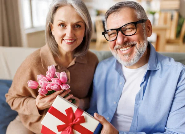 Любящий муж дарит цветы и подарочную коробку на день святого Валентина счастливой жене — стоковое фото