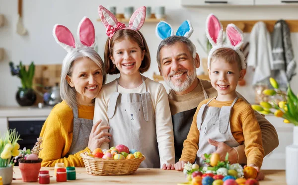 Tradizioni pasquali familiari. Felice nonni e bambini in orecchie di coniglio fasce dipingere le uova insieme — Foto Stock