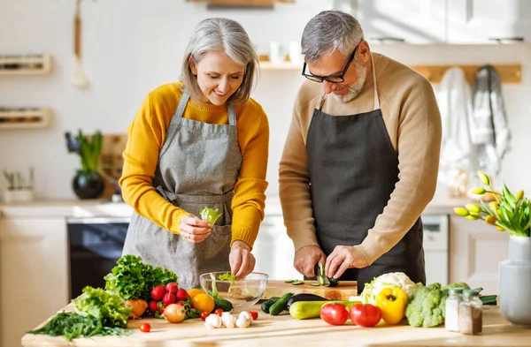 Glückliches älteres Ehepaar bereitet gemeinsam vegetarisches Abendessen zu und schneidet frisches buntes Gemüse — Stockfoto