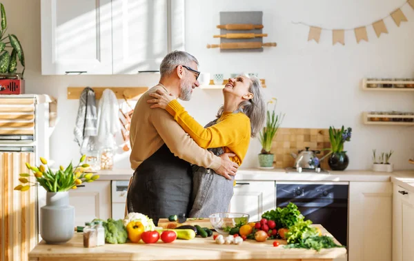 Glückliche Senioren Ehepaar Mann und Frau umarmen und tanzen beim gemeinsamen Kochen in der Küche — Stockfoto