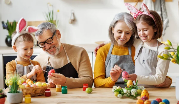 Boldog kisgyerekek, akik gyönyörű festett tojást készítenek húsvétra szerető idős nagyszülőkkel — Stock Fotó