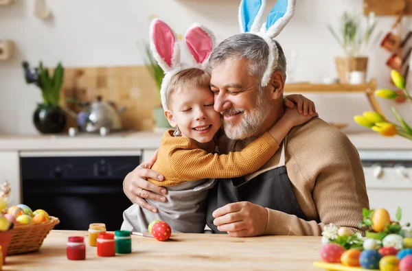 Felice famiglia amorevole nonno e carino nipotino bambino abbracciare mentre la pittura uova di Pasqua — Foto Stock