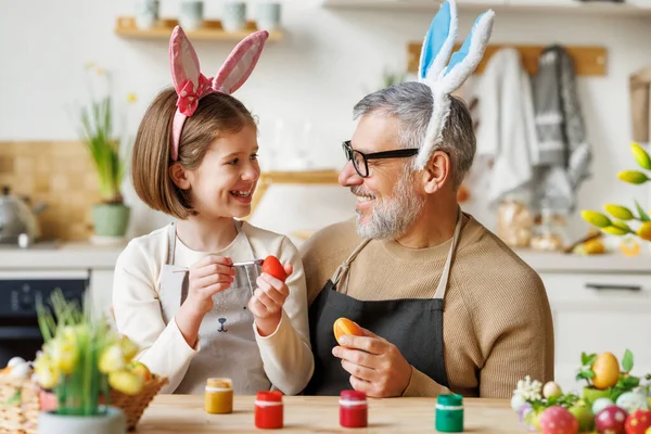 Amare nonno e bambino in fasce auricolari coniglio decorare le uova per Pasqua in luce accogliente cucina — Foto Stock