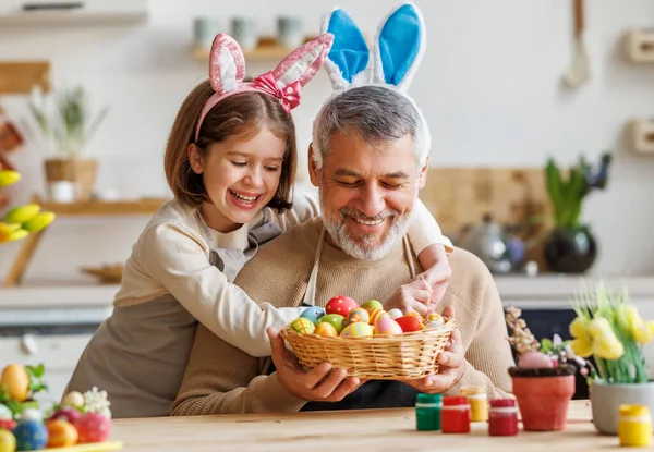 Mutlu aile büyükbaba ve küçük tatlı kız torun Paskalya yumurtası çizerken kucaklaşıyorlar. — Stok fotoğraf