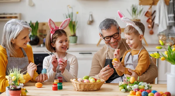 Счастливые маленькие дети создают красивые крашеные яйца к Пасхе с любящими старшими бабушками и дедушками — стоковое фото