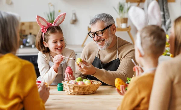 Feliz familia abuelo y pequeña nieta sosteniendo canasta de mimbre llena de huevos cocidos pintados — Foto de Stock