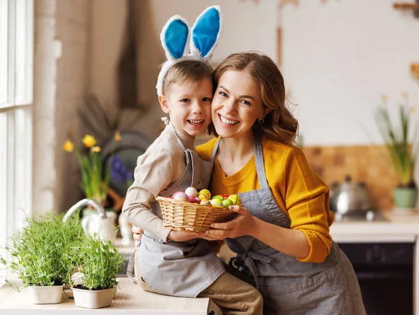 Sladký rodinný portrét mladé matky a malého syna s proutěným košem plným namalovaných velikonočních vajec — Stock fotografie