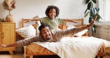 Mutlu Afro-Amerikan aile babası ve oğlu evde yatakta yatıyor.