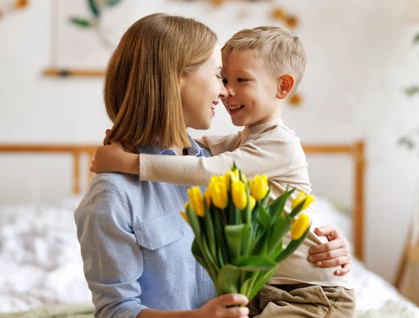 Grata madre con bouquet abbraccio figlio — Foto Stock