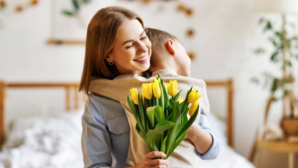 Agradecida madre con ramo de abrazo hijo — Foto de Stock