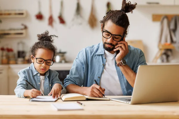 Giovane padre afro-americano che lavora in remoto su laptop con figlio bambino a casa — Foto Stock