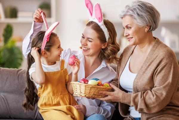 Famiglia felice in orecchie di coniglio ridere e giocare con le uova a casa durante la preparazione per le vacanze di Pasqua — Foto Stock