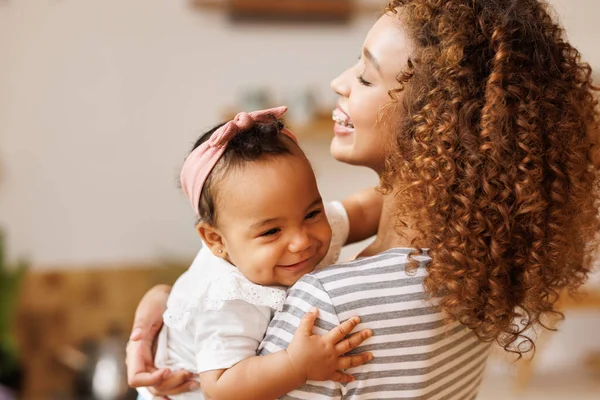 Feliz, alegre mãe étnica segura uma filha de bebê rindo em seus braços. — Fotografia de Stock