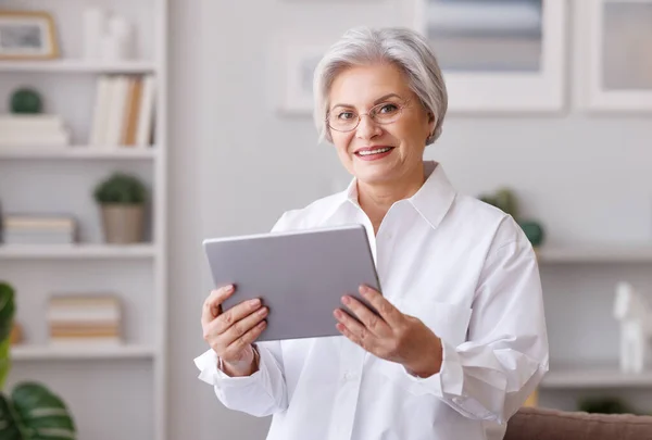 Lachende volwassen vrouw met behulp van tablet thuis — Stockfoto