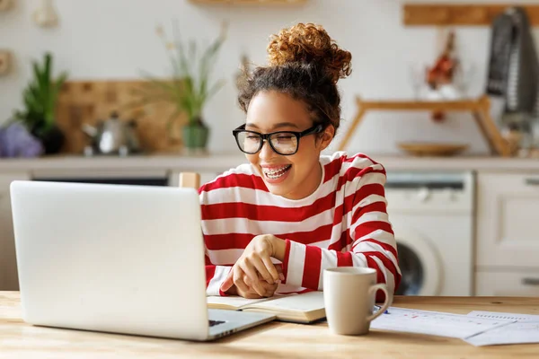 Mulher americana africana feliz sorrindo durante a aula on-line enquanto estudava em casa no laptop — Fotografia de Stock