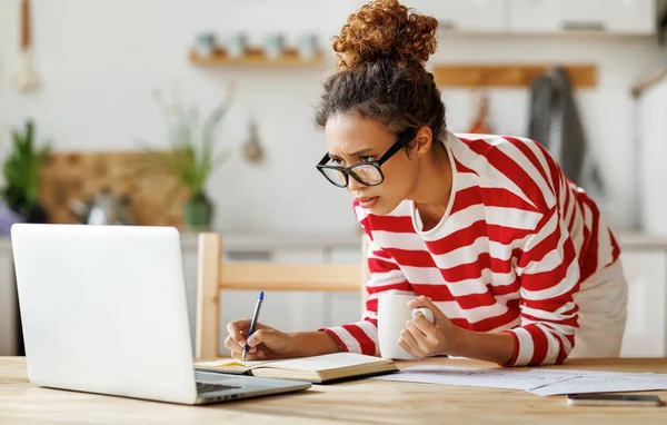 Gericht Afrikaans amerikaanse vrouwelijke freelancer op zoek naar laptop het nemen van notities tijdens remote team meeting — Stockfoto