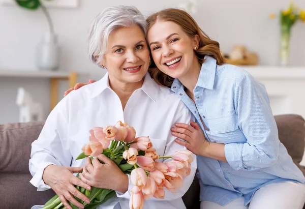 Encantada joven felicitaciones madre con ramo de tulipanes frescos —  Fotos de Stock