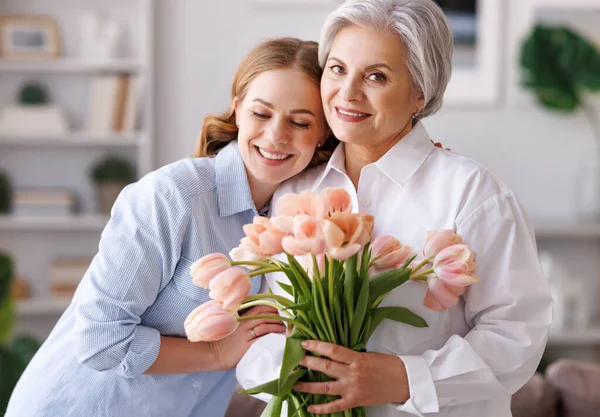 Jovem encantada parabéns mãe com buquê de tulipas frescas — Fotografia de Stock