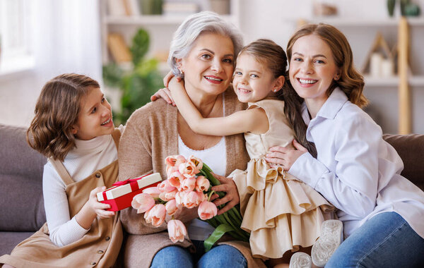 Happy International Womens Day. daughter and granddaughter giving flowers to grandmother celebrate Mothers Day 