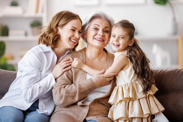 Szczęśliwa wielopokoleniowa rodzina: starsza kobieta z córką i wnuczką na kanapie — Zdjęcie stockowe