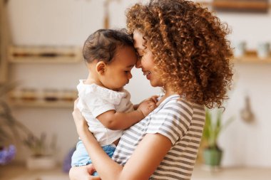 Mutlu, neşeli Afrikalı Amerikalı anne, gülen bir bebeği kollarında tutuyor. Annelik kavramı ve sevgi dolu bir aile.