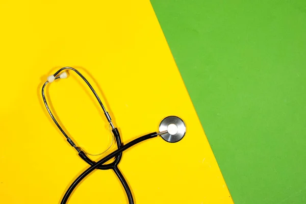 medical stethoscope isolated on yellow and green background