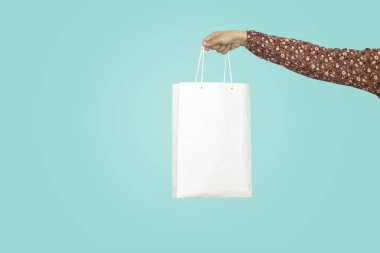 Alışveriş çantası tutan kadın mavi arka planda izole edilmiş.