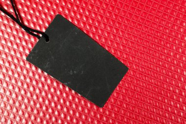 Siyah karton fiyat etiketi veya kırmızı deri arka planda izole edilmiş etiket