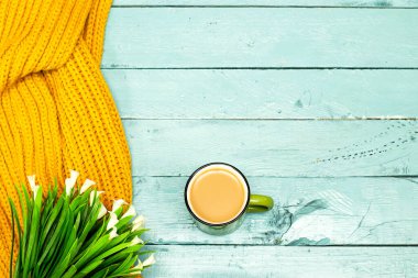Sütlü kahve fincanı, ahşap masadaki yün atkıda Calla Lili çiçeği. Merhaba kış konsepti