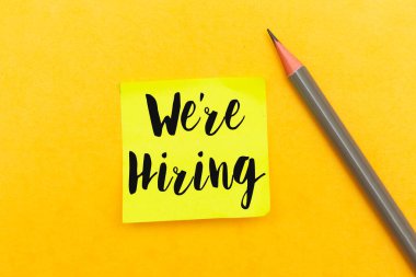 Sarı arka planda kalemle izole edilmiş yapışkan nota konsept işe alıyoruz.