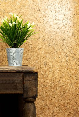 Eski ahşap masada saklanmış bir kap zambak çiçeği.