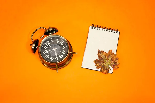 Alarm Clock Showing Clock Autumn Leaves Empty Notebook Isolated Orange — Stock Photo, Image