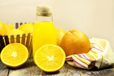 Tahta sepetin içinde taze meyvelerle dolu bir şişe taze portakal suyu.