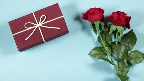 红玫瑰花礼品盒和蓝色背景白纸卡片的女士 — 图库视频影像