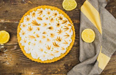 Ev yapımı limonlu pasta ve ahşap arka planda limon meyvesi.