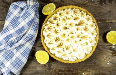 Ev yapımı limonlu pasta ve ahşap arka planda limon meyvesi.