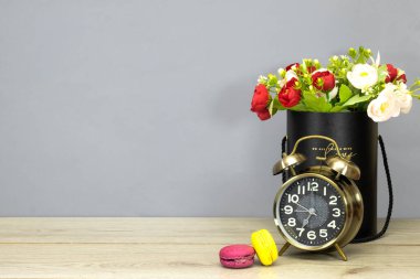 Siyah kutuda bir buket çiçek ve alarmlı kurabiyeler saat 7 'de ahşap masada görünüyor. Noel ve Yeni Yıl kutlamaları konsepti