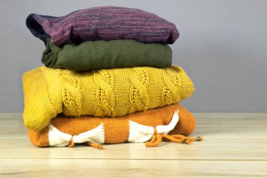 Temiz, yeni yıkanmış, düzgünce katlanmış kışlık giysiler ahşap masa, süveterler, yazı için yer.