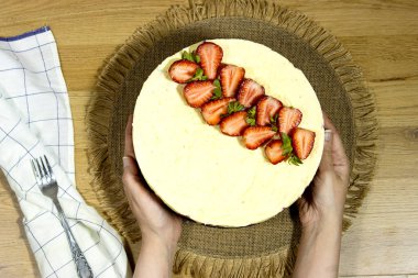 Eller Süngerli kek tutan kadın çilekli ve vanilyalı, Fransız dilinde Fraisier adında tatlı bir Fransız yemeği.