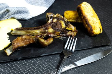 Izgara kuzu pirzola veya koyun ve patates kroket ve siyah tabakta gruyere peyniri.